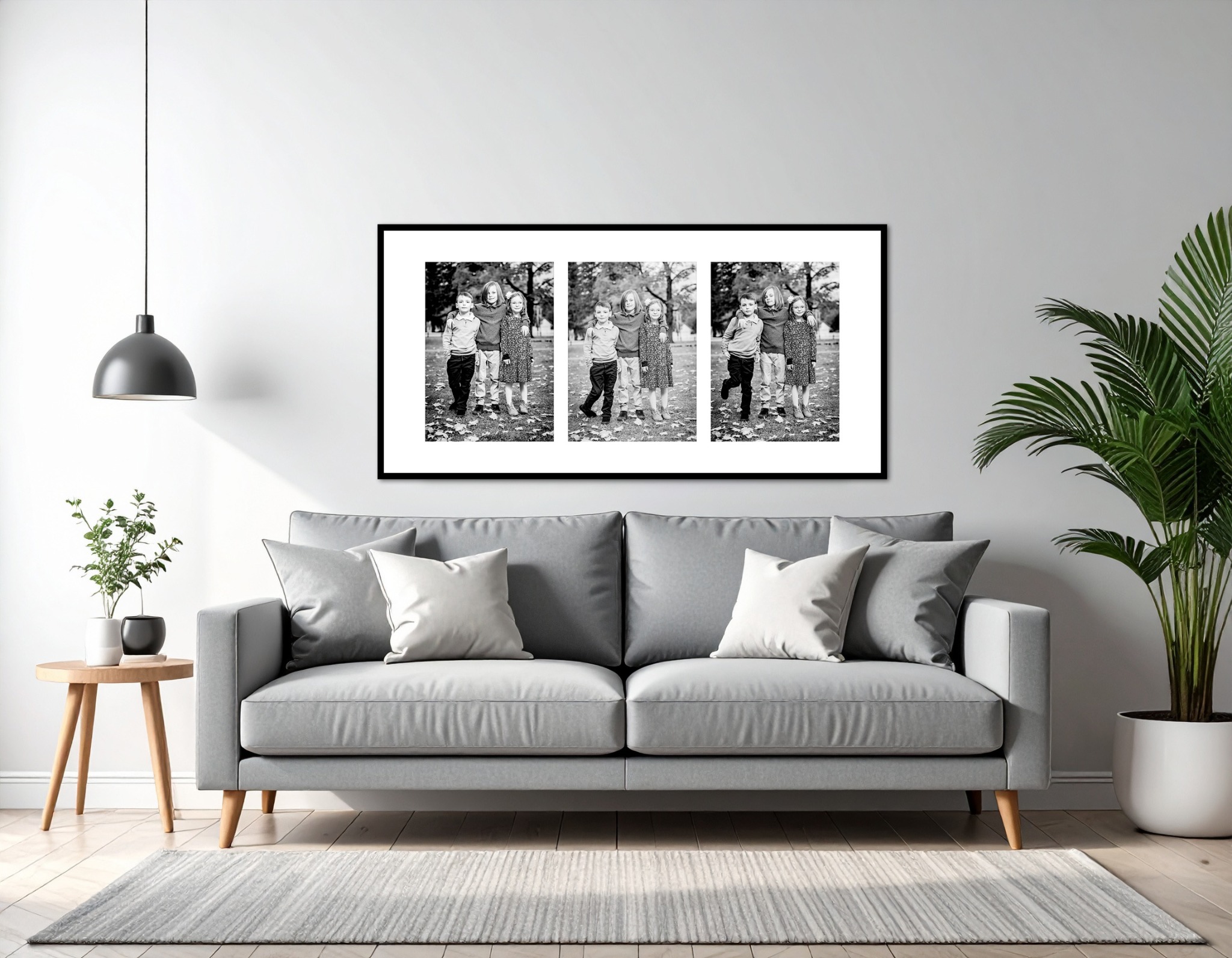 Three black-and-white family portraits framed above a gray living-room couch